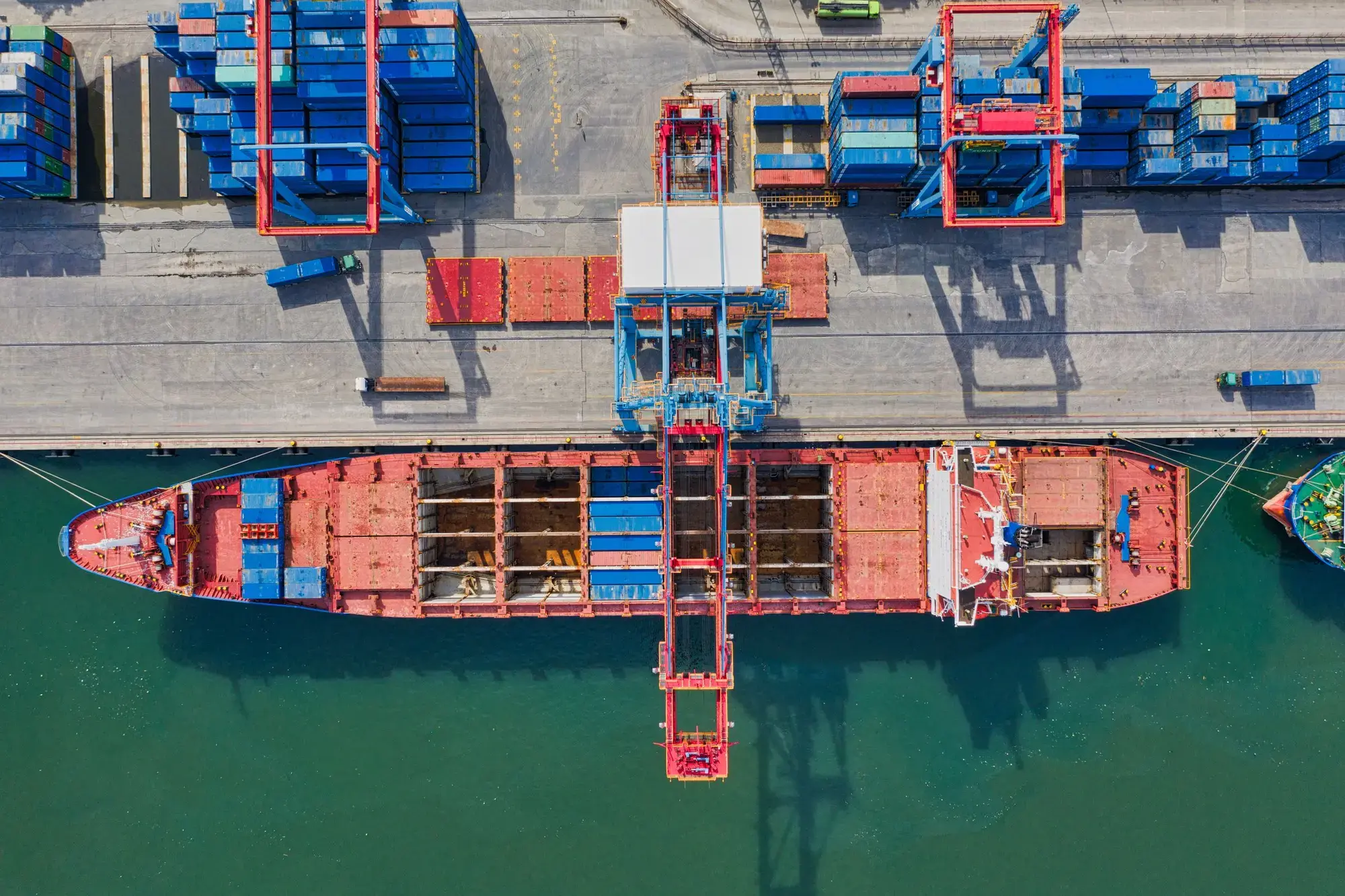 Cargo ship berthed alongside stacked intermodal containers at a port terminal